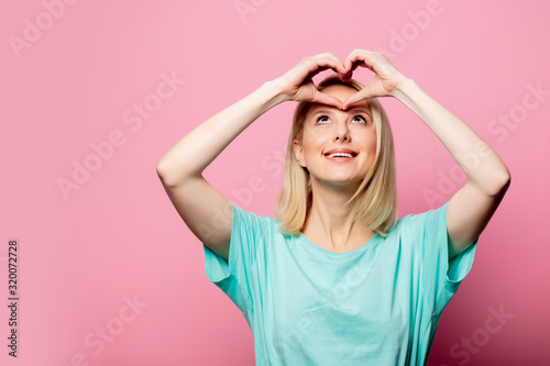 beautiful woman show love gesture on pink background © Masson