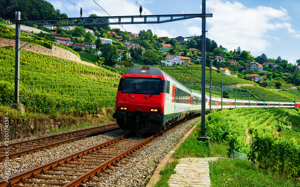 Naklejka premium Uruchomiony pociąg na linii kolejowej w pobliżu szlaku turystycznego Lavaux Vineyard Terraces, dystrykt Lavaux-Oron, Szwajcaria