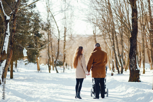 Elegant family in a winter forest. Mother with carriage. Man in a brown coat