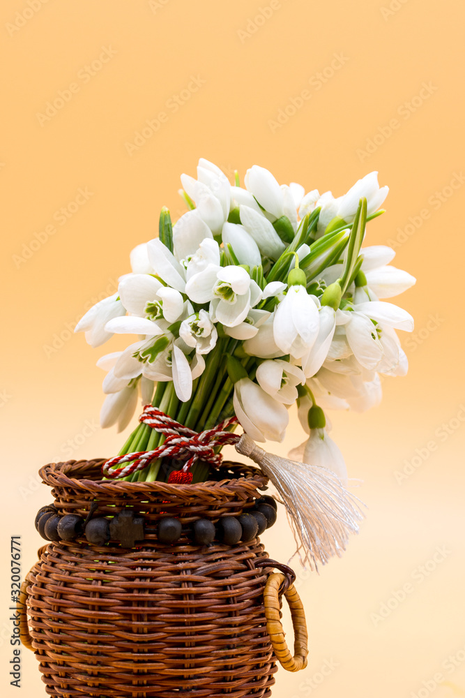 bouquet of snow drops in a basket on colored background with red and white string first of march celebration martisor concept