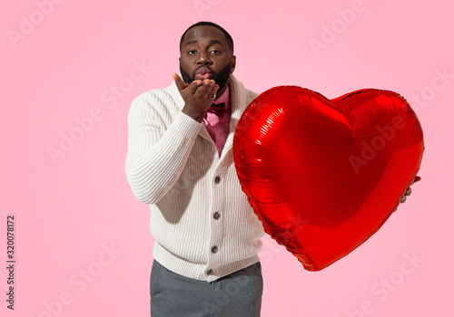 Happy man holds red heart shape balloon. Photo of handsome man in love on pink background. Valentine's Day © Romario Ien