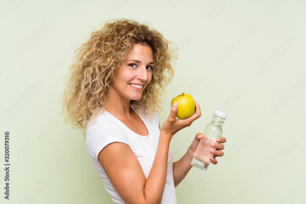 Young blonde woman with curly hair with an apple and with a bottle of water Young blonde woman with curly hair with an apple and with a bottle of water