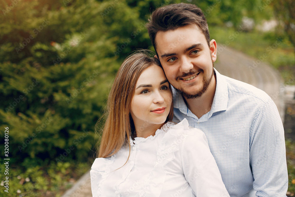 Fototapeta premium Cute couple in a park. Lady in a white dress. Guy in a white shirt