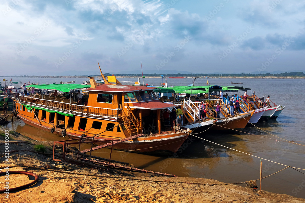 Φωτογραφία Traditional colorful Burmese boats on the Irrawaddy River, in the port of Mandalay, Myanmar, against a clear blue sky
