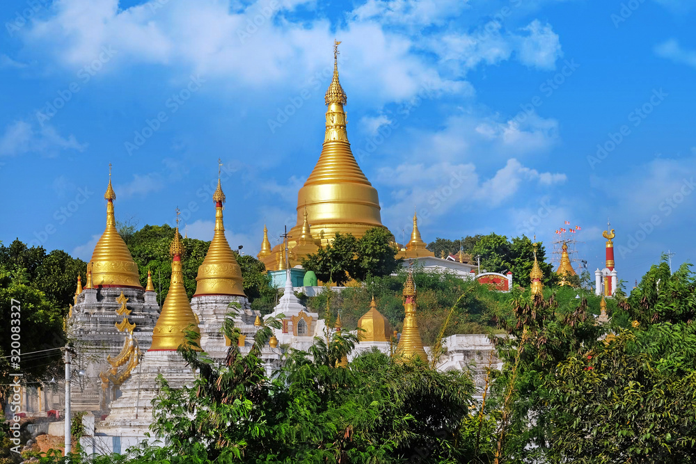 Naklejka premium View of the golden roof of a Burmese Pagoda in Mingun, Mandalay, against a blue sky.