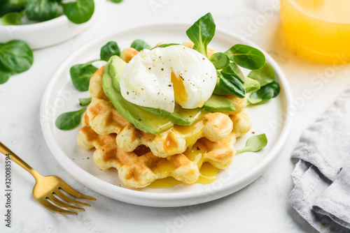 Poached egg with cheese waffles, avocado and corn salad on a white plate. Healthy breakfast. Close-up. Selective focus