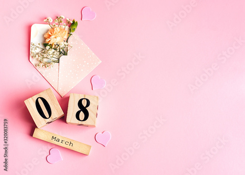Womens day composition. 8 march wooden calendar with flowers in an envelope on the pink background. Copy space, top view