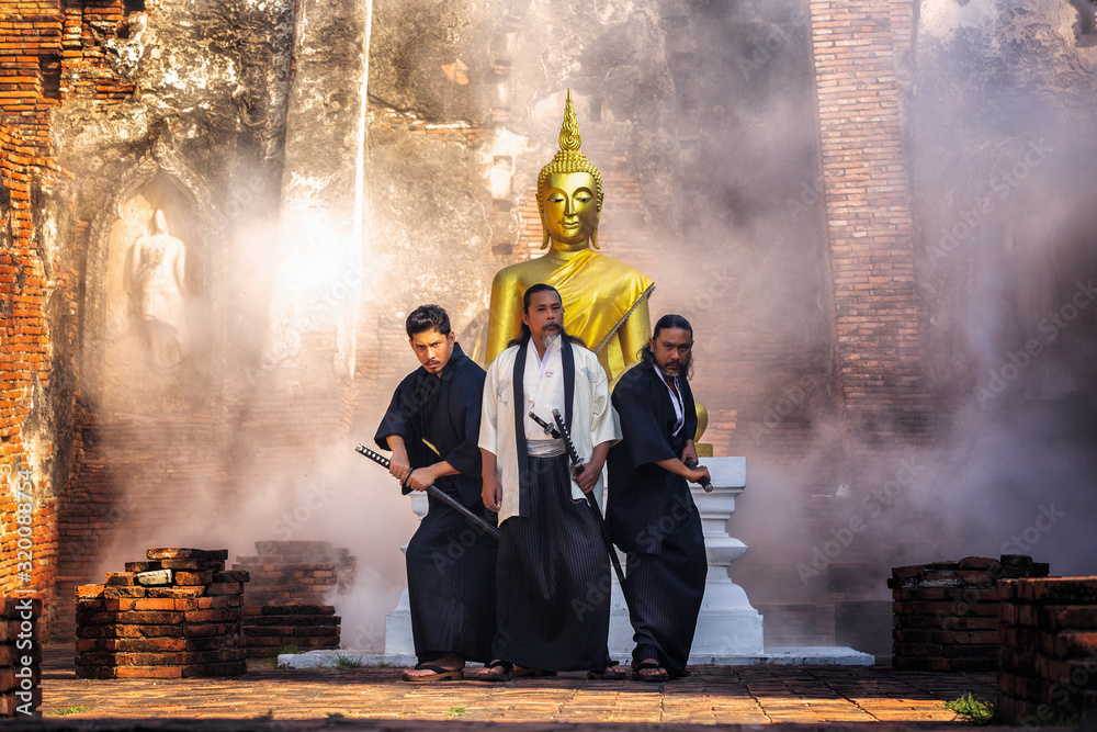 Obraz premium Samurai warrior standing with a sword in front of Buddha.