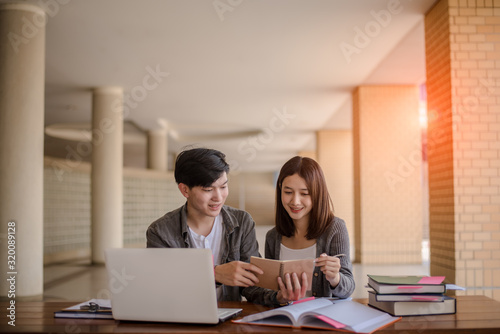 Two students doing homework together and helping each other sitting in a table at university
