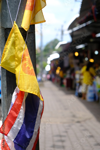 A closeup shot of a thai flag against a metal post at a market just outside Wat Phra That Doi Suthep. Market serves fresh street side food and ornately designed art and trinkets. Travelers purchase