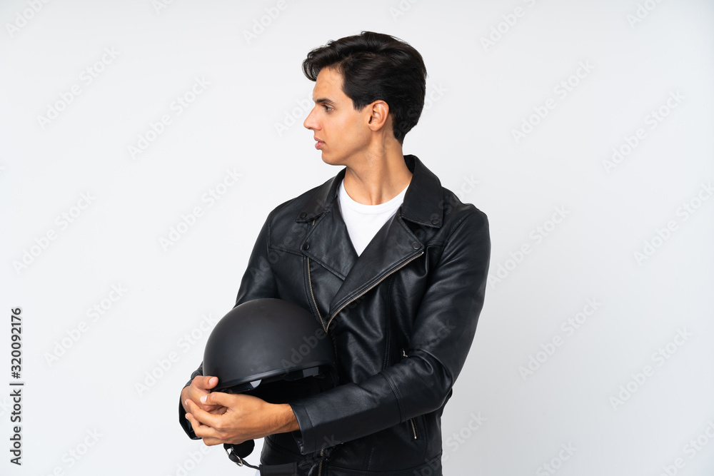 Man holding a motorcycle helmet over isolated white background looking side Man holding a motorcycle helmet over isolated white background looking side