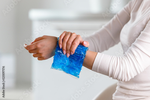 Schilderij op canvas Woman applying cold compress to a her painful wrist caused by prolonged work on the computer, laptop, copy space