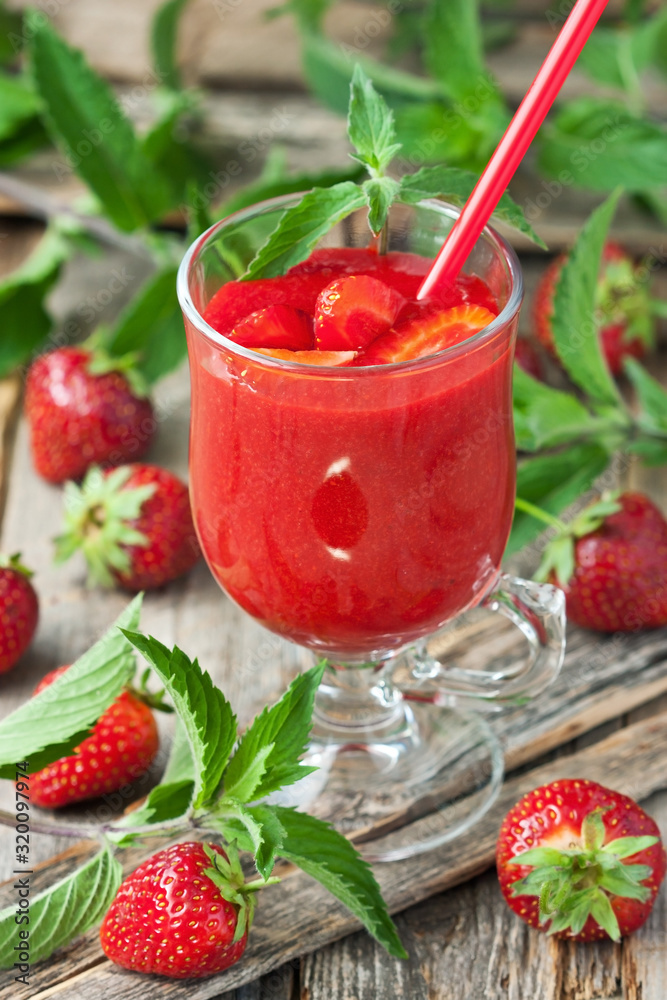 Strawberry smoothie in glass with mint leaves on wooden background Strawberry smoothie in glass with mint leaves on wooden background