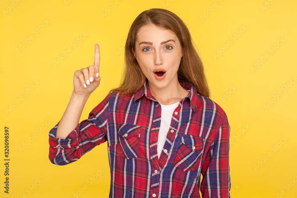 Eureka, excellent idea! Portrait of inspired smart ginger girl in checkered shirt pointing finger up and looking amazed at camera, got sudden solution, creative thoughts. studio shot yellow background Eureka, excellent idea! Portrait of inspired smart ginger girl in checkered shirt pointing finger up and looking amazed at camera, got sudden solution, creative thoughts. studio shot yellow background