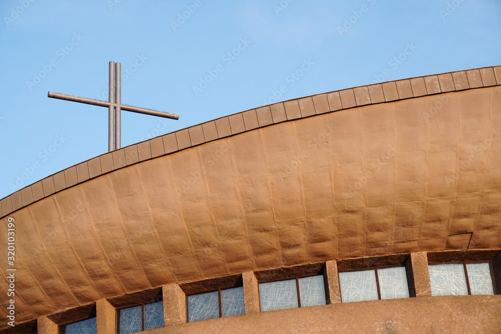 Fototapeta premium Round Church building with a cross in the rays of the setting sun against the blue sky.