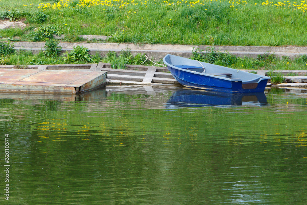 Blue dinghy at the shore, near the metal Pantone. Summer sunny day. Blue dinghy at the shore, near the metal Pantone. Summer sunny day.