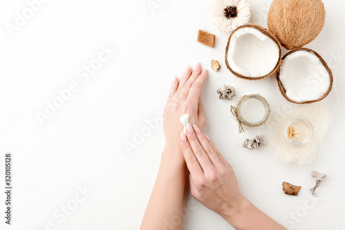 Woman apply the moisturizing cream consist of cocount ingredients to her hands.