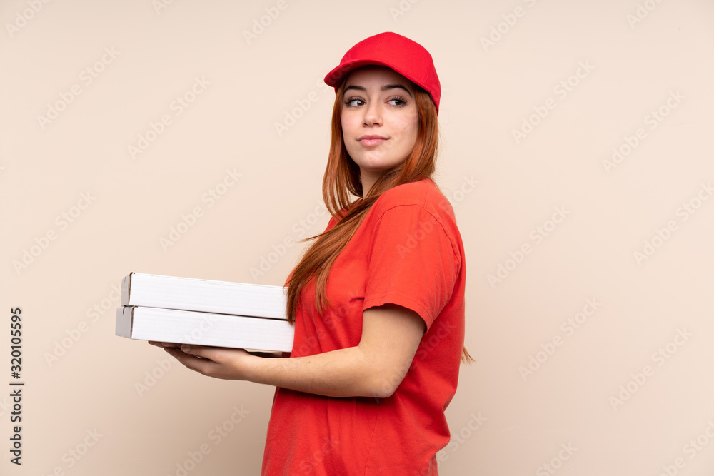 Pizza delivery teenager girl holding a pizza over isolated background laughing Pizza delivery teenager girl holding a pizza over isolated background laughing