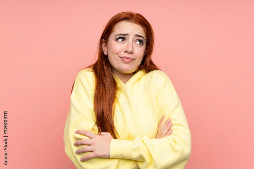 Redhead teenager girl over isolated pink background making doubts gesture while lifting the shoulders Redhead teenager girl over isolated pink background making doubts gesture while lifting the shoulders
