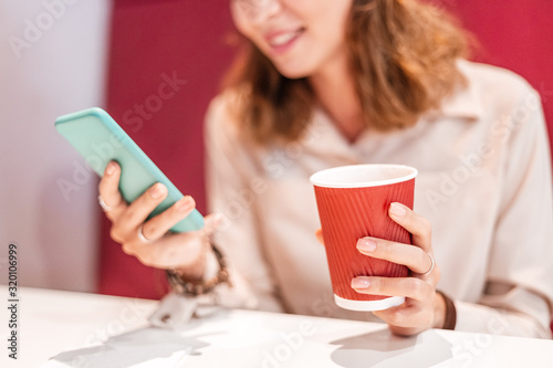 Asian woman having a break in coffee shop. Reading news in her smartphone