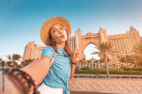 Photography Happy asian girl traveller taking selfie photo with the famous luxury Atlantis hotel building on a Jumeirah Palm Island in Duba, UAE