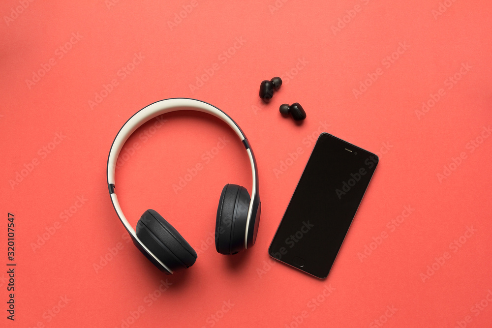 Stock photo of a bluetooth headphones and a smartphone on a red background Stock photo of a bluetooth headphones and a smartphone on a red background