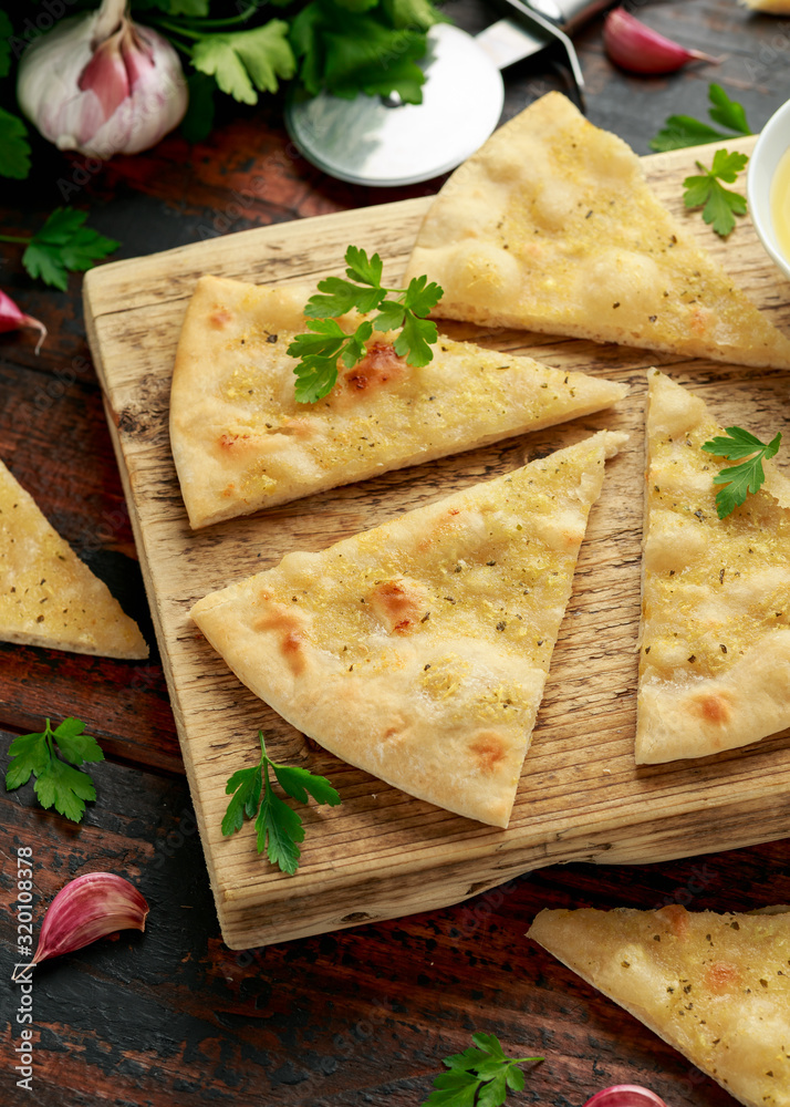 Fresh slices of Garlic pizza on wooden board with herbs. Fresh slices of Garlic pizza on wooden board with herbs.