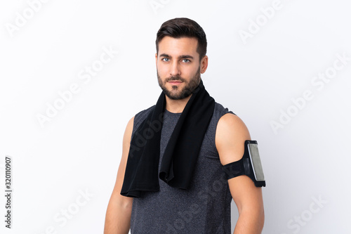 Young sport handsome man with beard over isolated white background with sport towel © luismolinero
