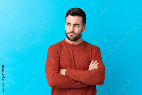 Young handsome man with beard over isolated blue background thinking an idea