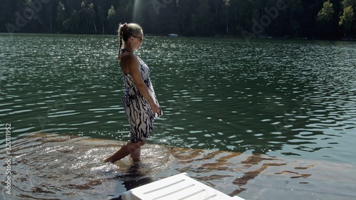 Woman lie on a sunbed in sunglasses and a boho silk shawl. Girl rest on a flood wood underwater pier. The pavement is covered with water in the lake.