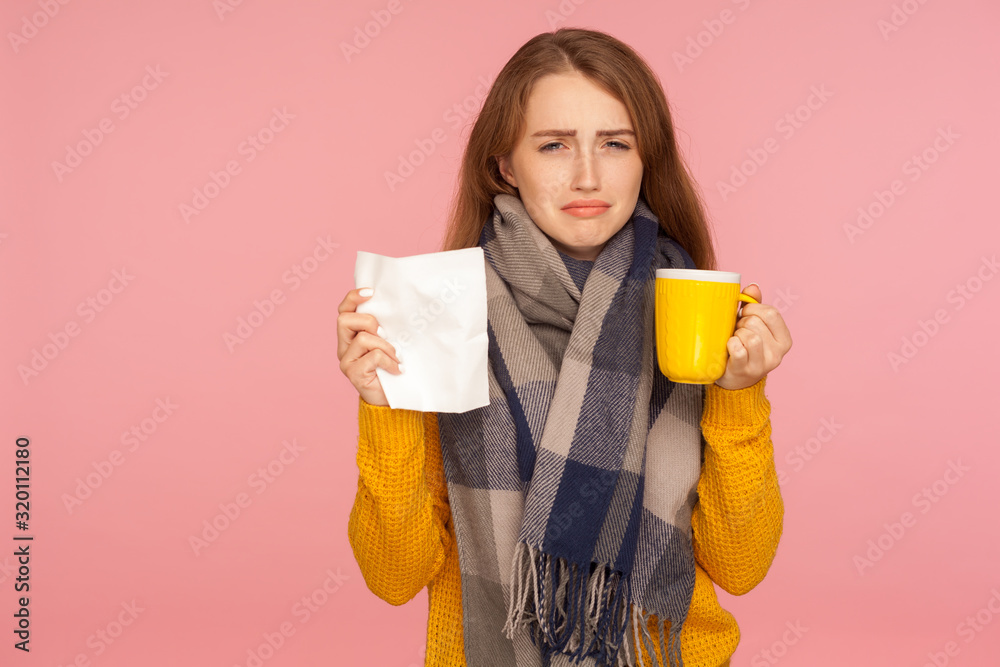 Influenza treatment. Portrait of unhealthy ginger girl wearing big scarf, holding napkin and cup with hot tea, treating flu and high temperature, healthcare. indoor studio shot, pink background Influenza treatment. Portrait of unhealthy ginger girl wearing big scarf, holding napkin and cup with hot tea, treating flu and high temperature, healthcare. indoor studio shot, pink background