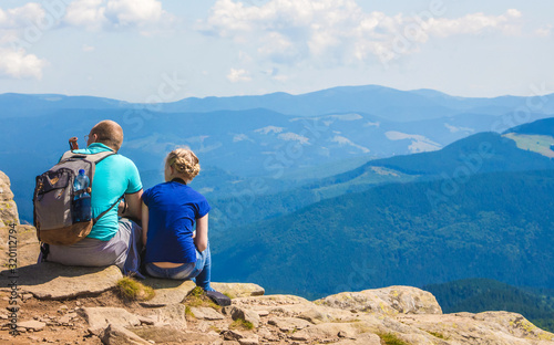 Dad and daughter sitting on a rock on a background of blue mountains_