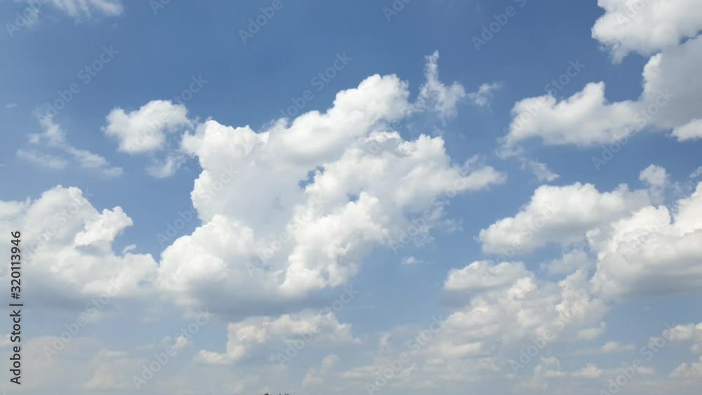 Blue summer sky with dense thick thunderstorm rain clouds moving across the heavens. Fast cloud formation and movement creating a surreal time lapse.