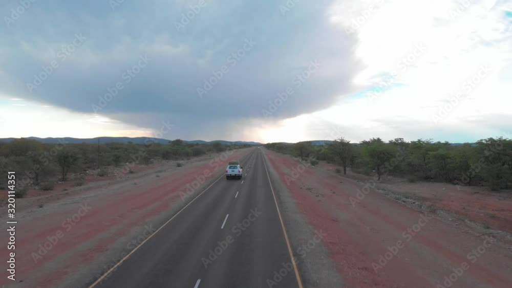 A vehicle driving towards a storm in the wilderness A vehicle driving towards a storm in the wilderness