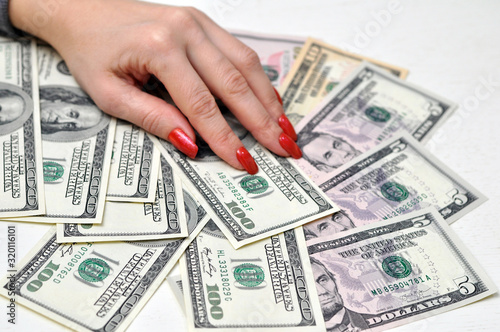 Female fingers with long artificial manicured nails hold a wad of money.