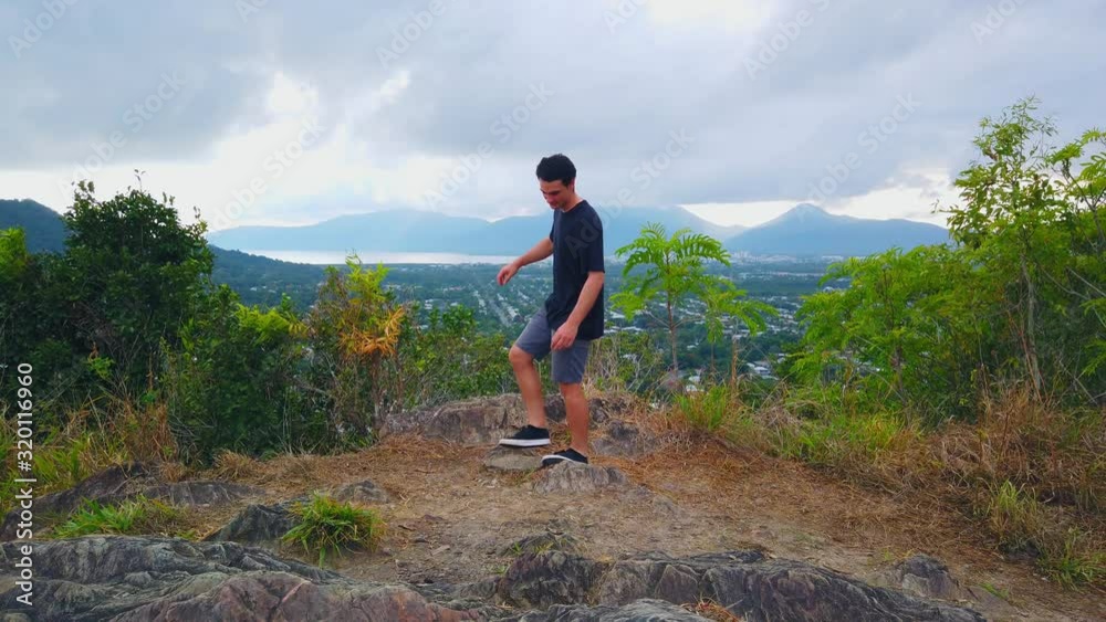 man at a lookout showing cairns australia overcast and early in the morning with the ocean and mountains in the distance turns to leave the lookout in slow motion man at a lookout showing cairns australia overcast and early in the morning with the ocean and mountains in the distance turns to leave the lookout in slow motion