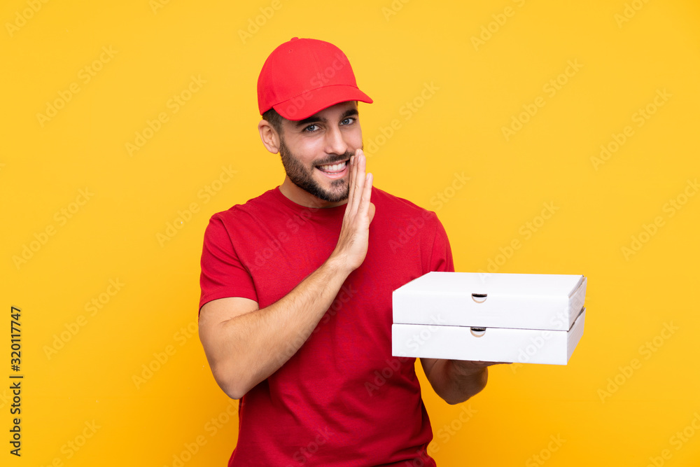 pizza delivery man with work uniform picking up pizza boxes over isolated yellow background whispering something pizza delivery man with work uniform picking up pizza boxes over isolated yellow background whispering something