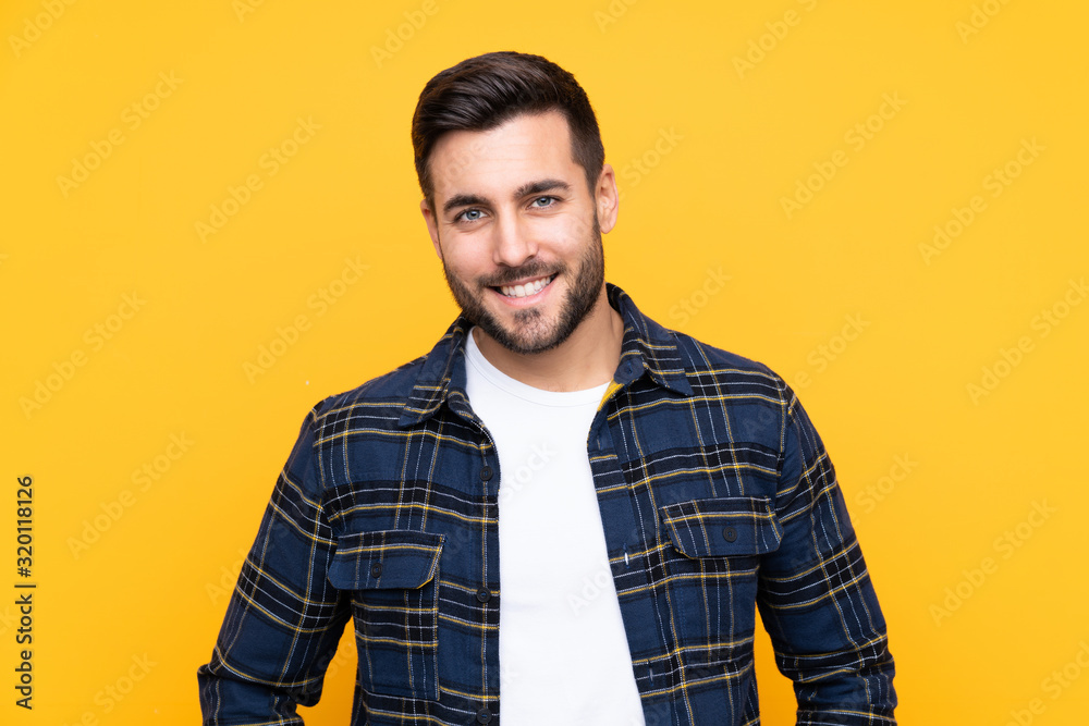 Young handsome man with beard over isolated yellow background laughing - obrazy, fototapety, plakaty 
