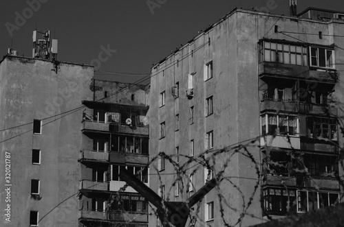 black and white photo of a house behind barbed wire