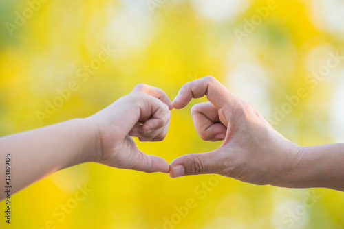 Mother and son make hand in hand heart shape naturally blur the background. Love concept.
