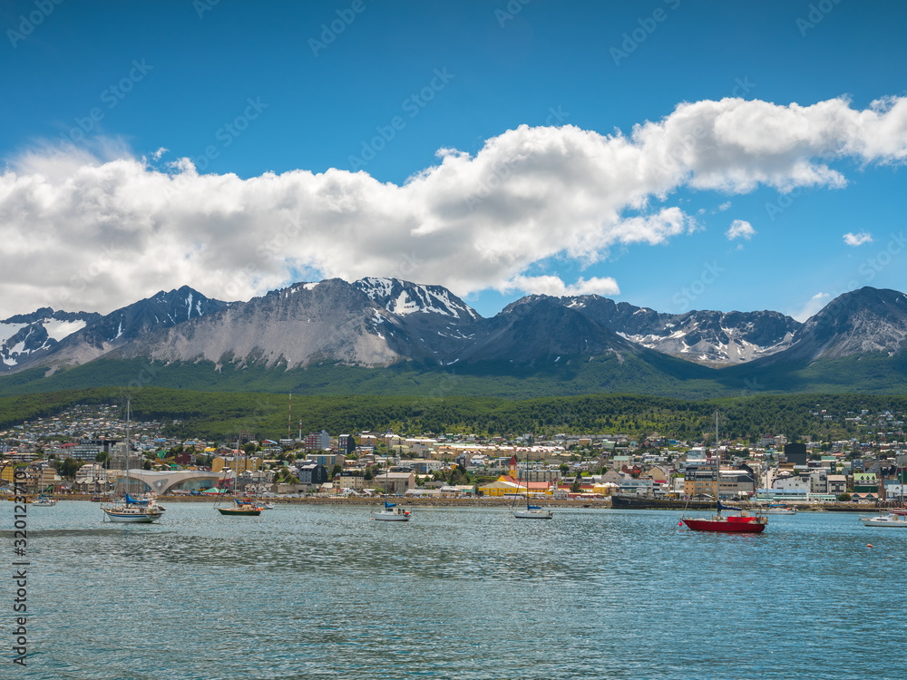 summer day with clouds and blue sky above yachts in harbor in Ushuaia