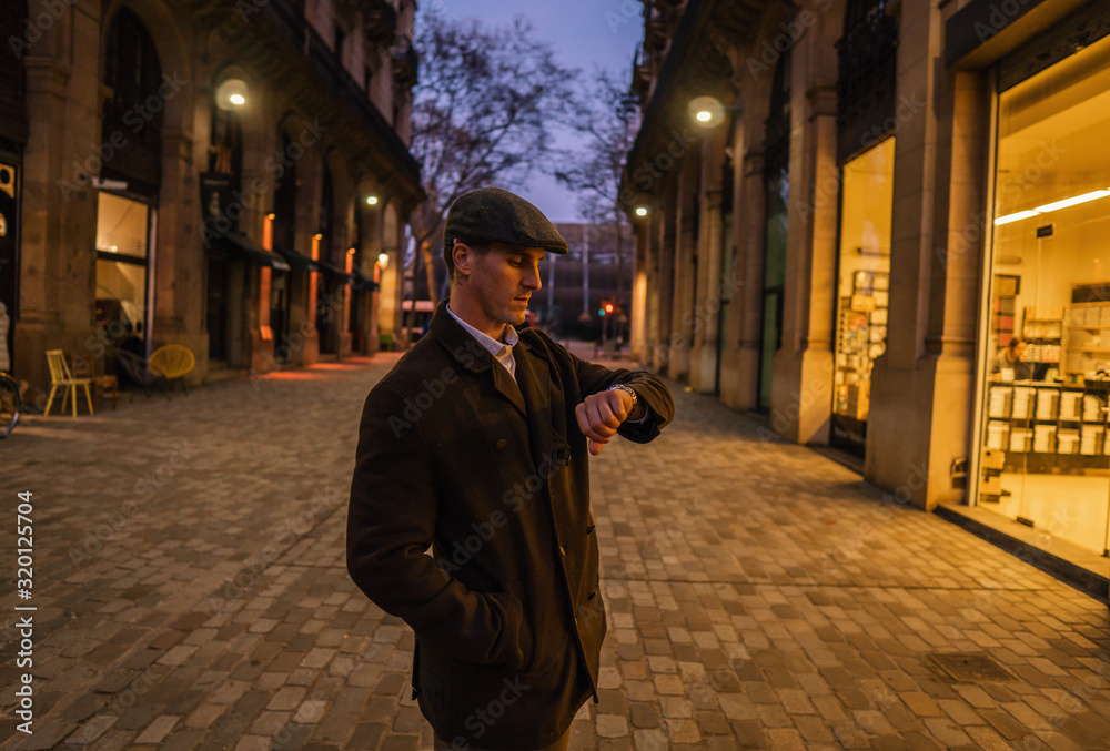 Old Fashion Man from the 1920s england walking along an old street of a historic city. He is checking time on wristwatch