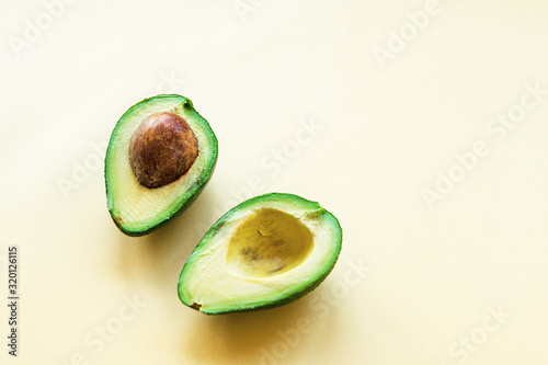 Two halves of cut avocado on a yellow background. Healthy food, raw, vegan. Copy space.