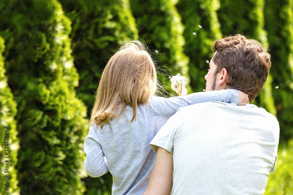 Back view. Father and daughter blowing dandelion flowers. Back view. Father and daughter blowing dandelion flowers.