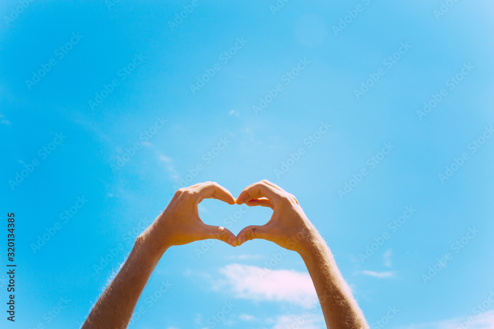 Heart shape making of hands against blue sky Men hands Heart shape making of hands against blue sky Men hands