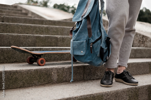 Teenager girl with backpack sitanding on the steps near her skate photo