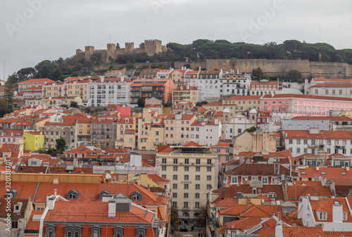 Views of the houses with tiled roofs and colorful facades in Lisbon, with the castle of San Jorge in the top of the hill