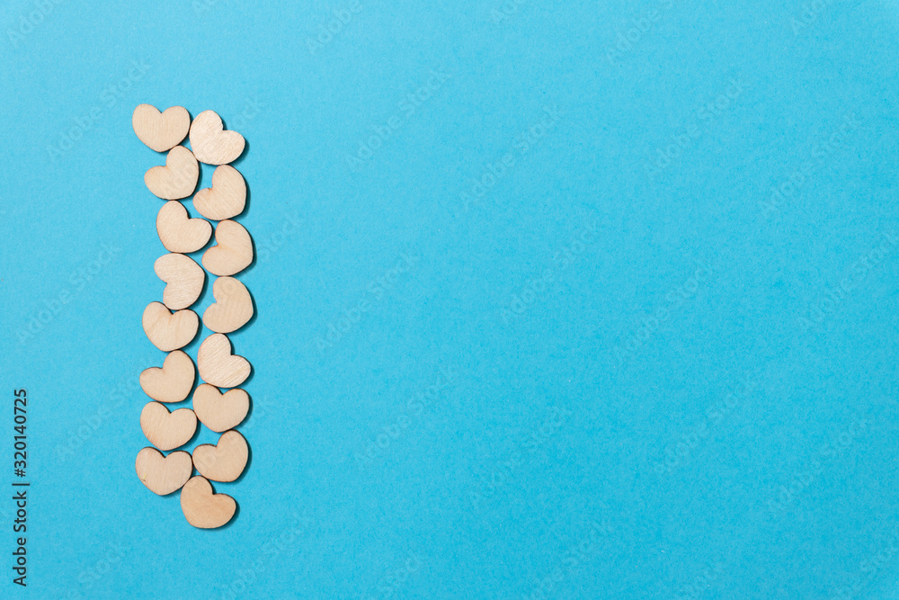 A lot of tiny wooden hearts on a blue background. A lot of tiny wooden hearts on a blue background.