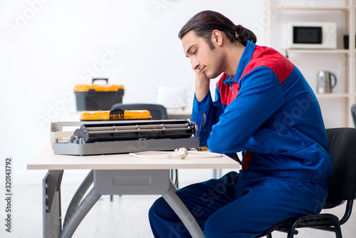 Young repairman repairing air-conditioner at warranty center