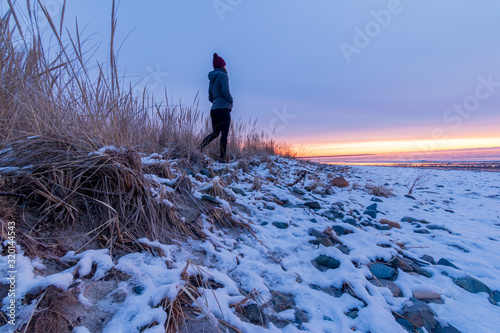 Winter sunrise on Drakes Island Beach, Maine with person silhouette.